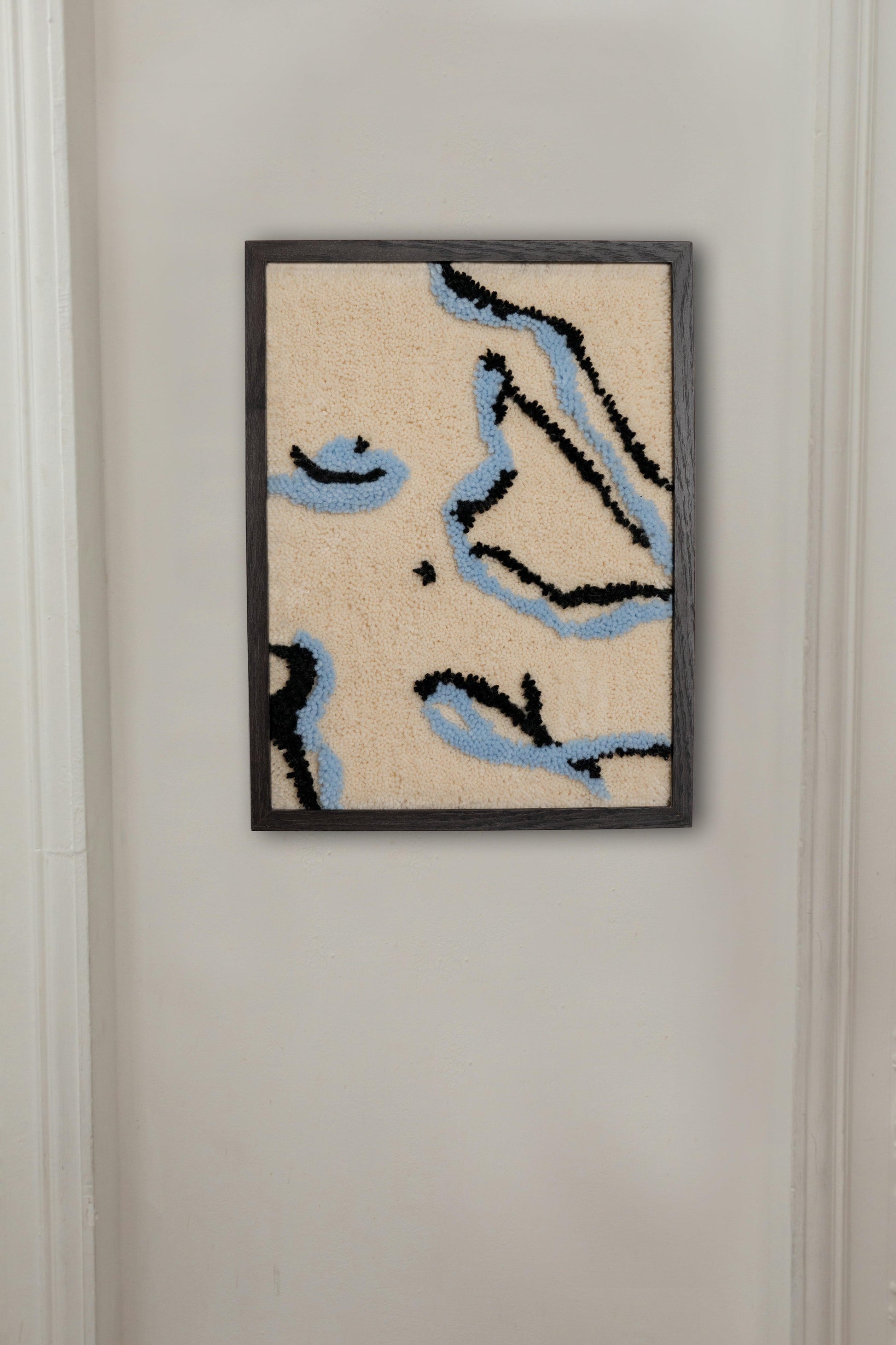 Tufted fabric artwork of a female body in double-line silhouette, framed in black. Dimensions 320mm x 420mm.