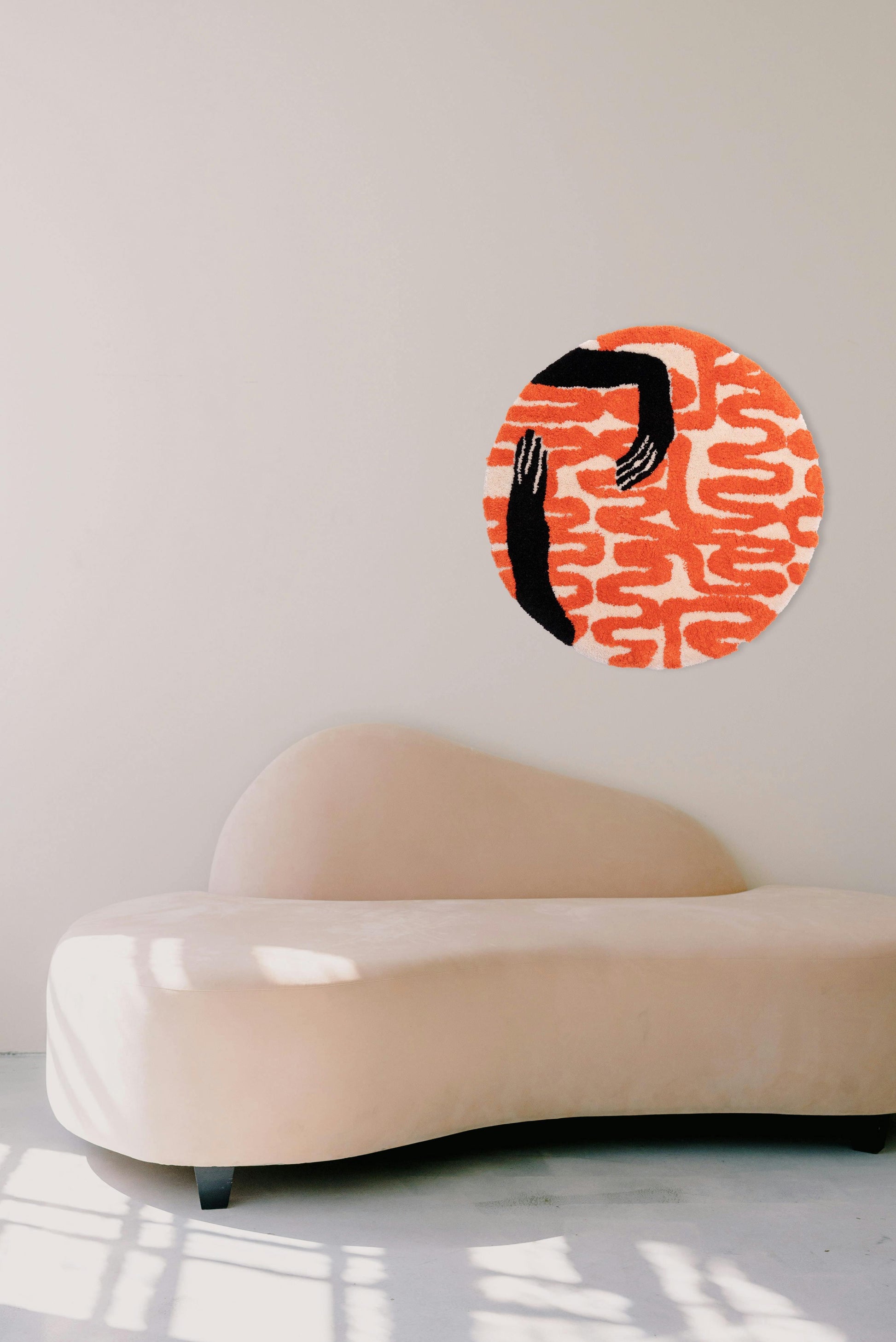 Tufted fabric wall hanging of abstract holding hands in black and orange. Dimensions 750mm x 750mm.